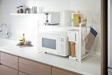 Yamazaki's white counter organizer sitting atop a microwave in a kitchen